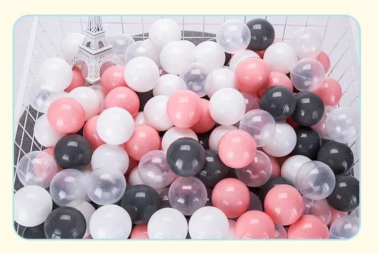 A large assortment of colorful plastic balls in various shades of pink, white, and gray are displayed in a white basket.