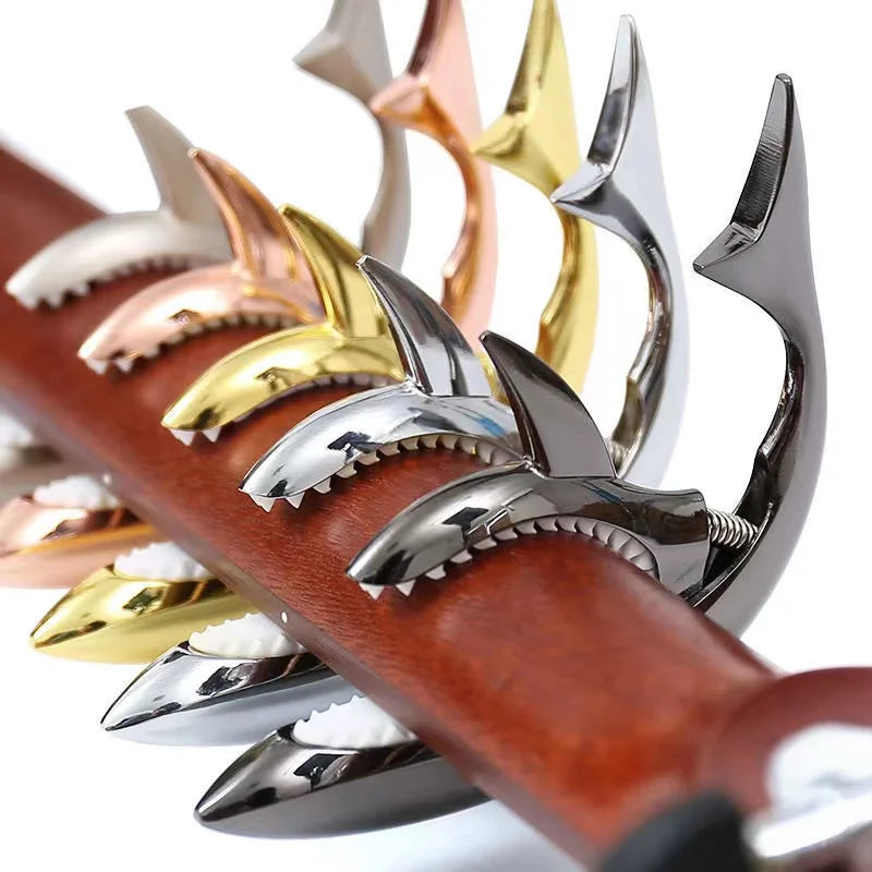 A close-up view of various pro-grade zinc alloy guitar capos with different finishes mounted on a wooden neck.