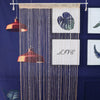 A beaded string curtain with a dark blue background featuring a heart design and the word LIVE.