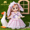 A pink fashion doll with long hair and a floral dress stands next to a white goose in a green, grassy setting.