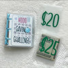 A clear binder and envelope containing money for a savings challenge, displayed on a white towel.