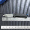 A carbon fiber folding knife with an axis lock is shown resting on a measuring ruler.
