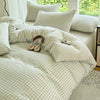 A light green and white gingham striped duvet cover set with two matching pillows on a bed.