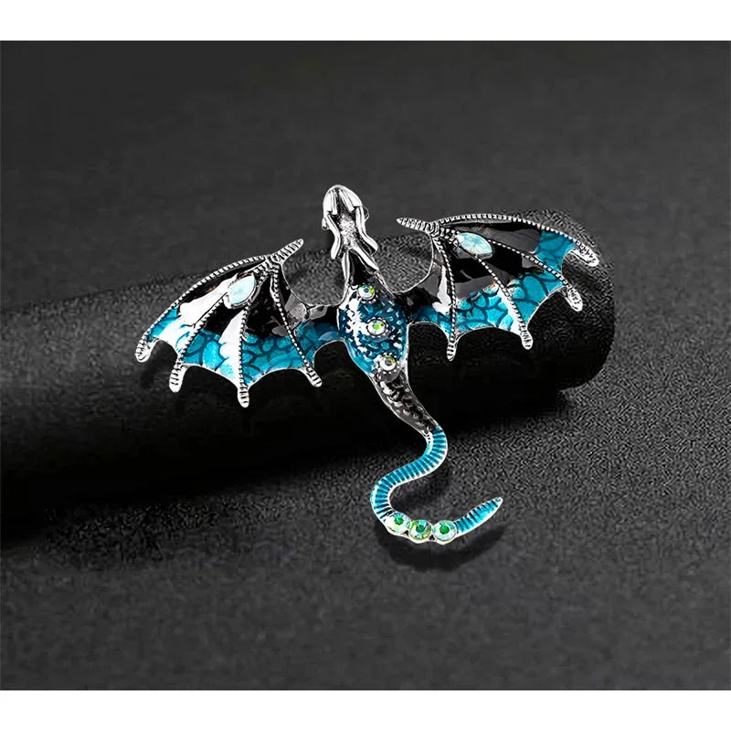 Silver enamel dragon brooch with iridescent blue and green accents on a black background