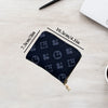 A dark blue compact zippered card holder wallet is shown on a light wooden surface with dimension lines.