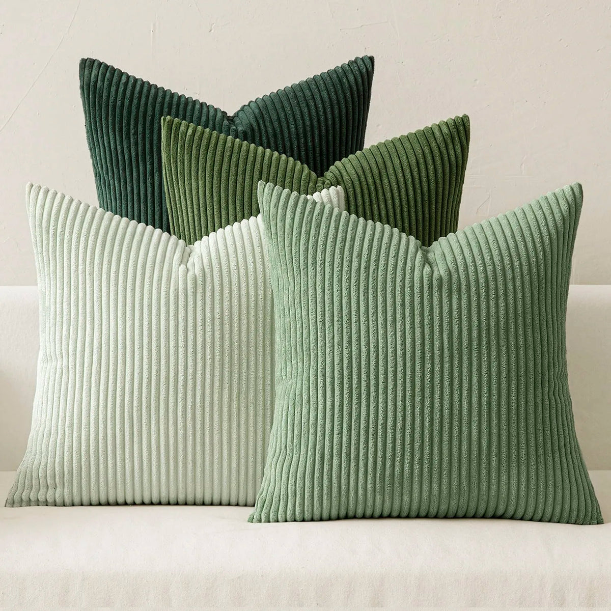 A grouping of three vertical ribbed throw pillows in shades of sage green and pale mint green.