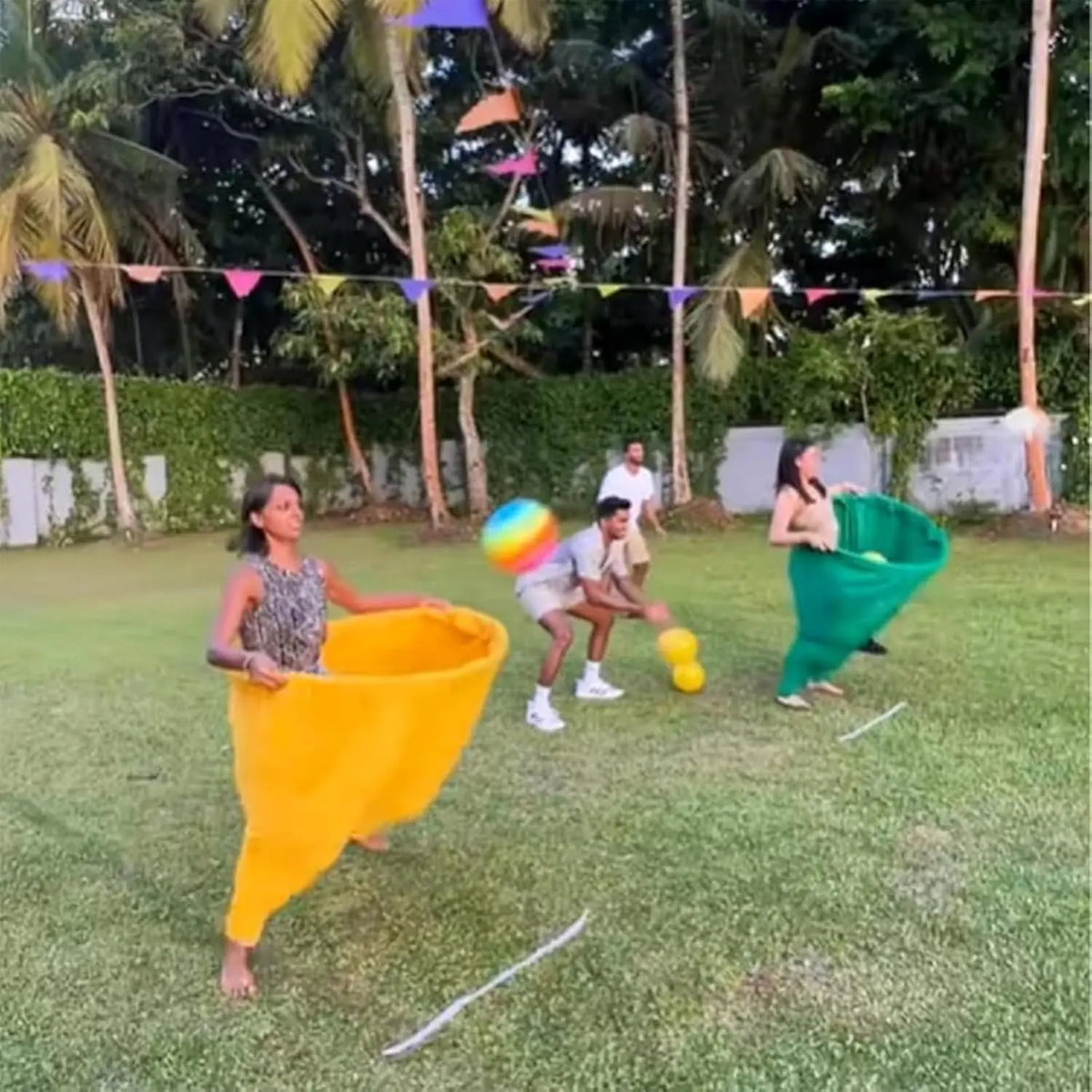 A woman in a yellow outfit is playing a pitching game with another person on a grassy field.