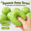 A hand squeezes a bright green squishy stress relief ball, highlighting its soft, glossy texture.