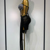 A black, sheer party outfit displayed on a gold mannequin featuring a beaded shoulder detail.