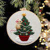 A handcrafted Christmas embroidery kit featuring a small mouse nestled in a green pine tree potted in a red ceramic pot.