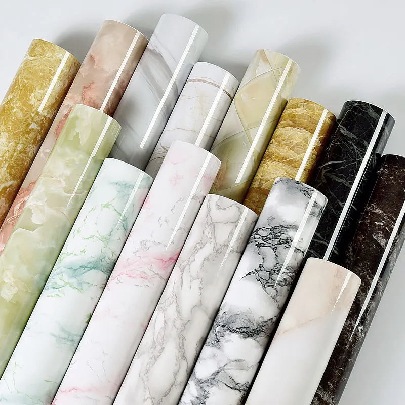A collection of rolls of waterproof self-adhesive marble wallpaper in various shades and patterns.