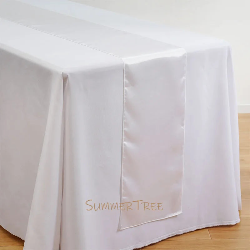 Elegant satin table runner in white fabric draped over a table.