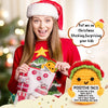 A woman in a red sweater is holding a handmade crochet animal doll with a positive message card.
