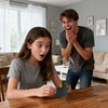 A young woman is holding an open box of a funny middle finger surprise prank gift on a wooden table.