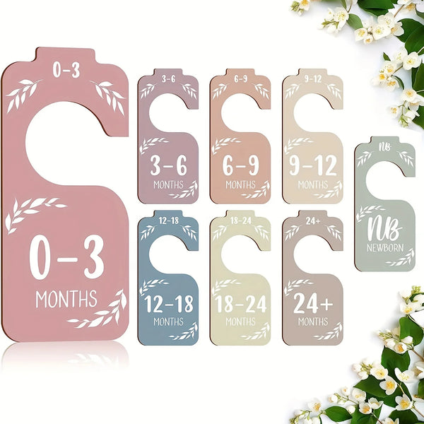 A set of wooden baby closet dividers with age markers 0-3, 3-6, 6-9, 9-12, 12-18, 18-24, and 24+ months.