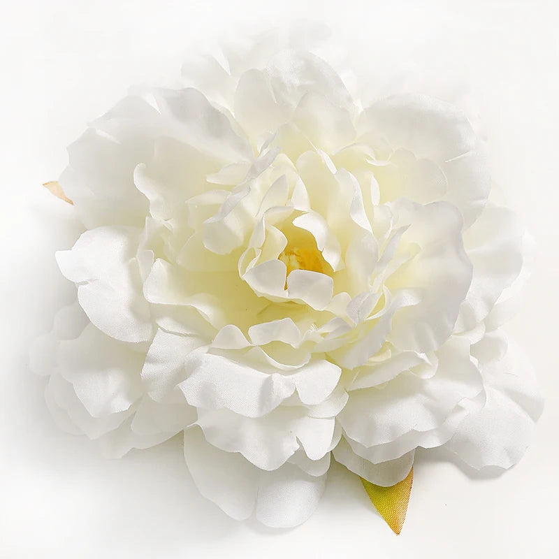A close-up of a white silk peony flower head with green accents.