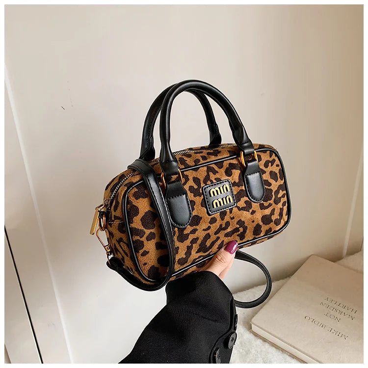 A brown and black retro leopard print hobo satchel bag being held by a hand.