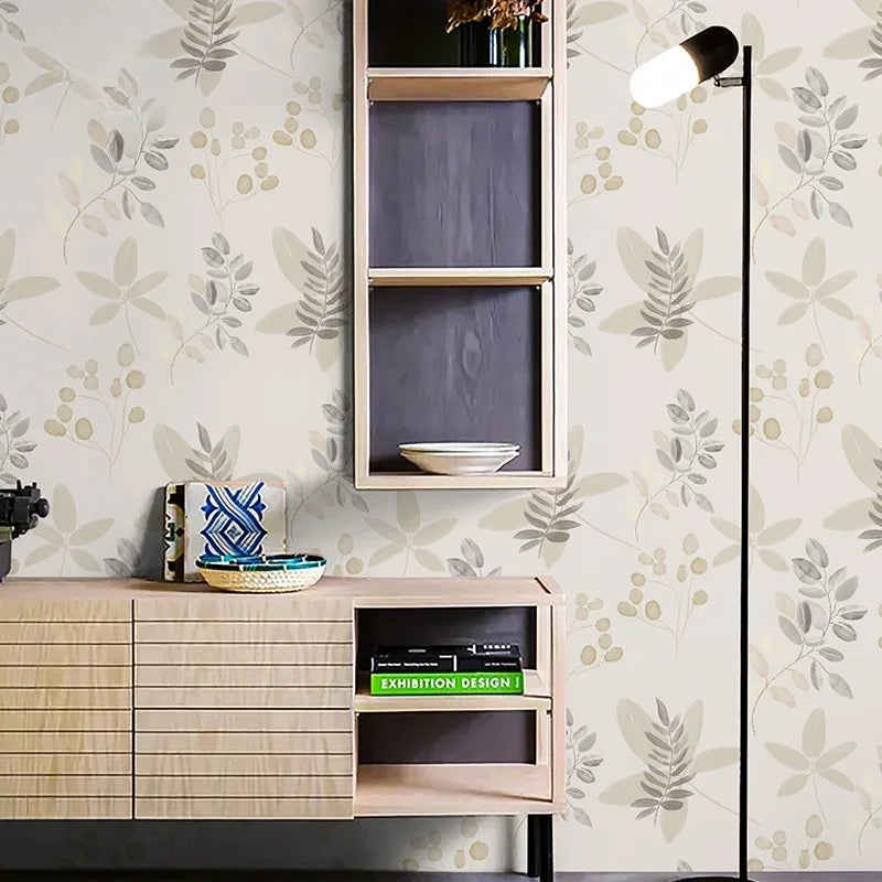 A wall features a light beige wallpaper with a pattern of green and white leaves, next to a wooden shelf unit and a modern wa