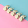A row of beige space-saving cascading hanger connector hooks arranged diagonally on a pink and blue background.