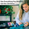 A woman is looking down at a portable sewing kit with various tools laid out on a dark surface.