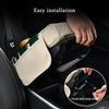 Hand installing a beige car armrest cushion with cupholders and storage features.
