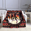 A black and orange printed flannel throw blanket featuring silhouettes of the Kiss band members.