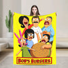 A yellow throw blanket featuring a cartoon illustration of three characters and the text Bob's Burgers