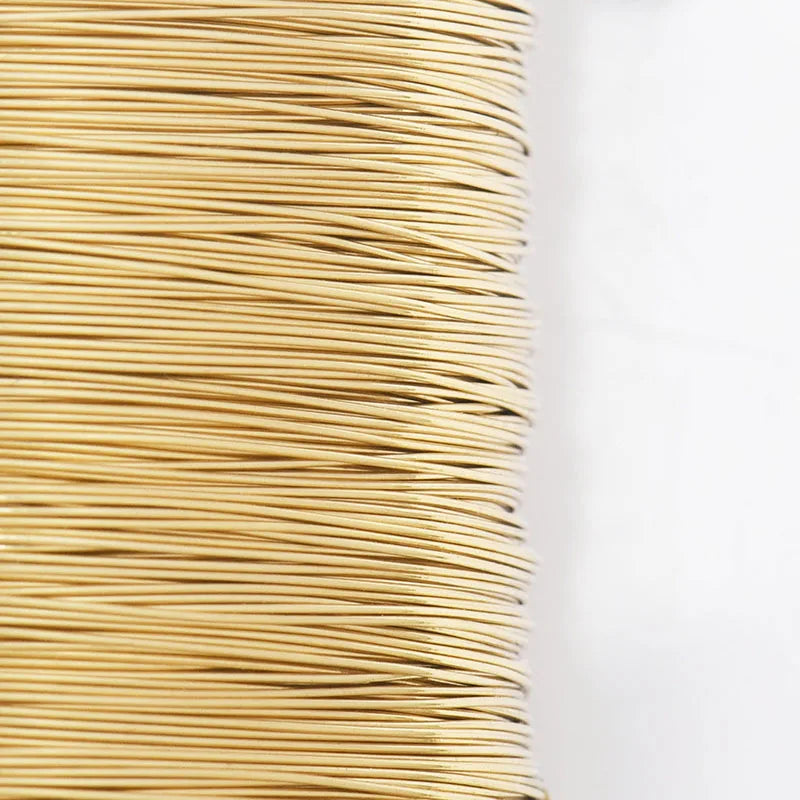 A tightly wound spool of thin, golden copper-clad steel sculpting wire.