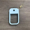 Light blue silicone protective case for a hand sanitizer spray attached to a gold keyring