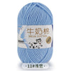 A ball of light blue milk cotton blend yarn with a label featuring a cartoon dog.