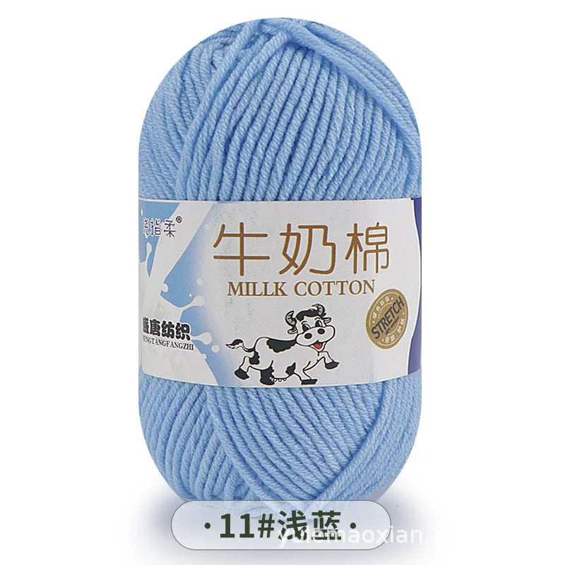 A ball of light blue milk cotton blend yarn with a label featuring a cartoon dog.