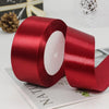 A roll of deep red satin ribbon used for gift wrapping or DIY crafts.