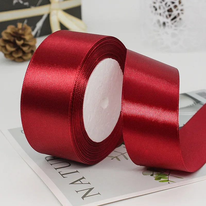 A roll of deep red satin ribbon used for gift wrapping or DIY crafts.