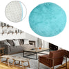 A bright turquoise shaggy round rug placed on a modern living room floor with a sofa and wooden furniture.