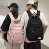 A person is shown from the back carrying a pink backpack and a black backpack.