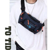 A person wearing a white sweatshirt is holding a dark blue tactical chest bag with an orange strap and silver chain.