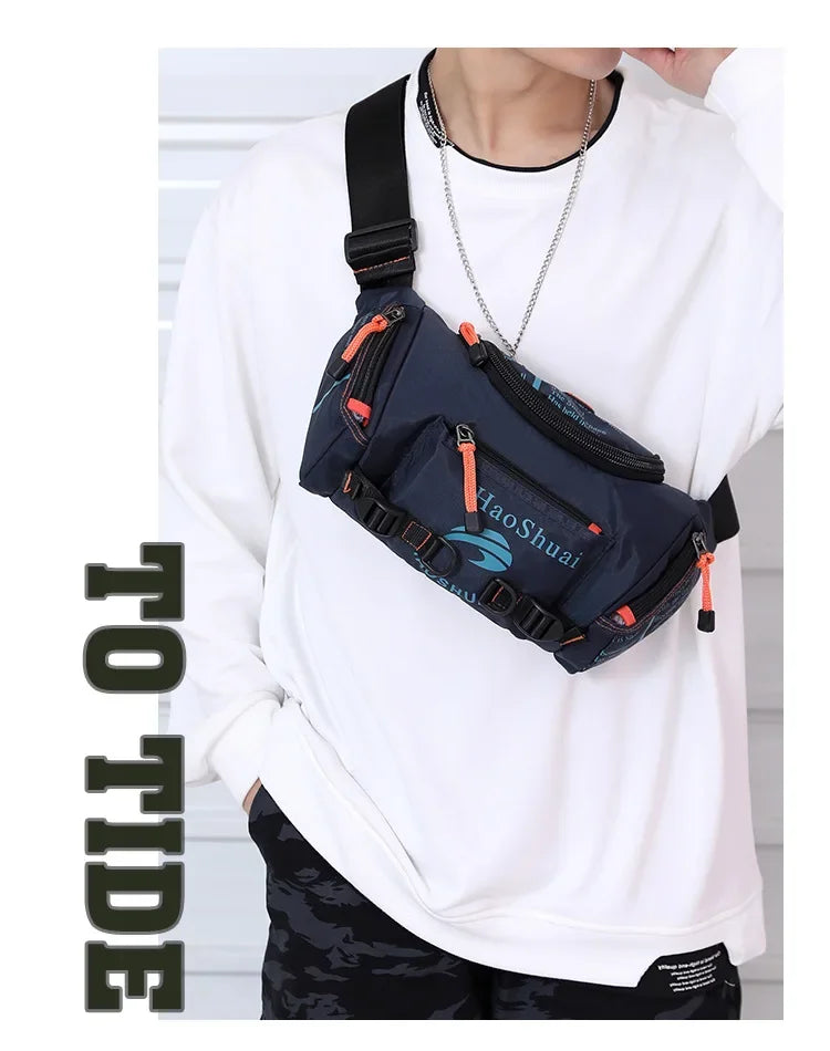 A person wearing a white sweatshirt is holding a dark blue tactical chest bag with an orange strap and silver chain.