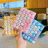 A hand holds a pink and blue cartoon keycap fidget keychain featuring various cute animal designs.
