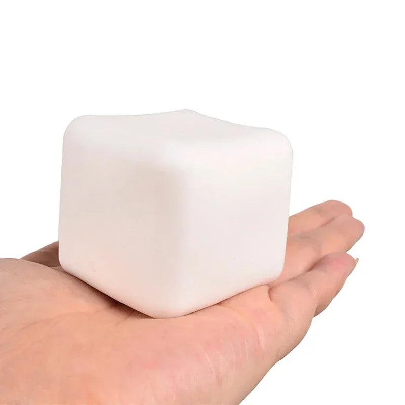 A hand is holding a white, square squishy milk tofu stress relief fidget toy.