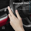 A hand is gripping a black steering wheel cover with a carbon fiber texture, highlighting premium feel and durability feature