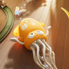 An orange interactive dancing octopus toy with light features is shown on a wooden floor.