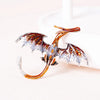 An enamel dragon brooch with iridescent scales and rhinestone accents is displayed on a white surface.