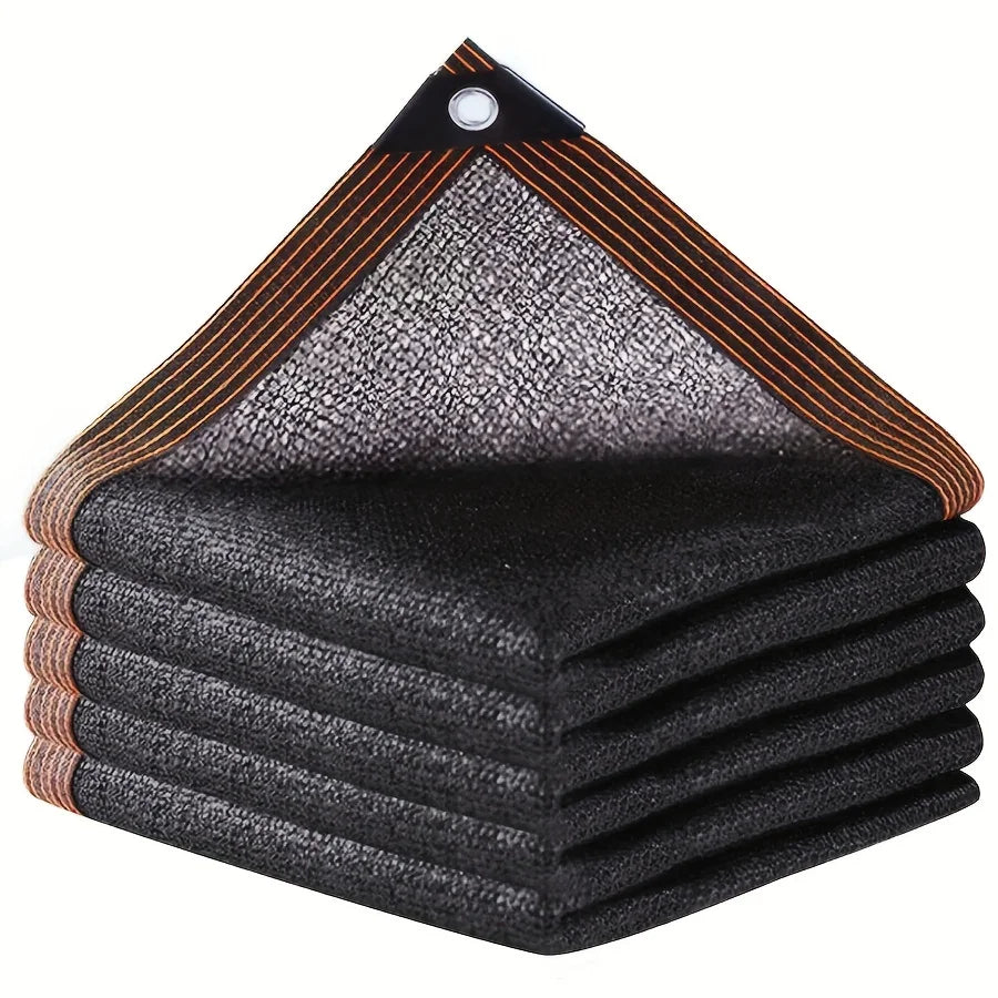 A stack of black shade cloth with reinforced edges and grommets, showing the fabric texture and striped edges.