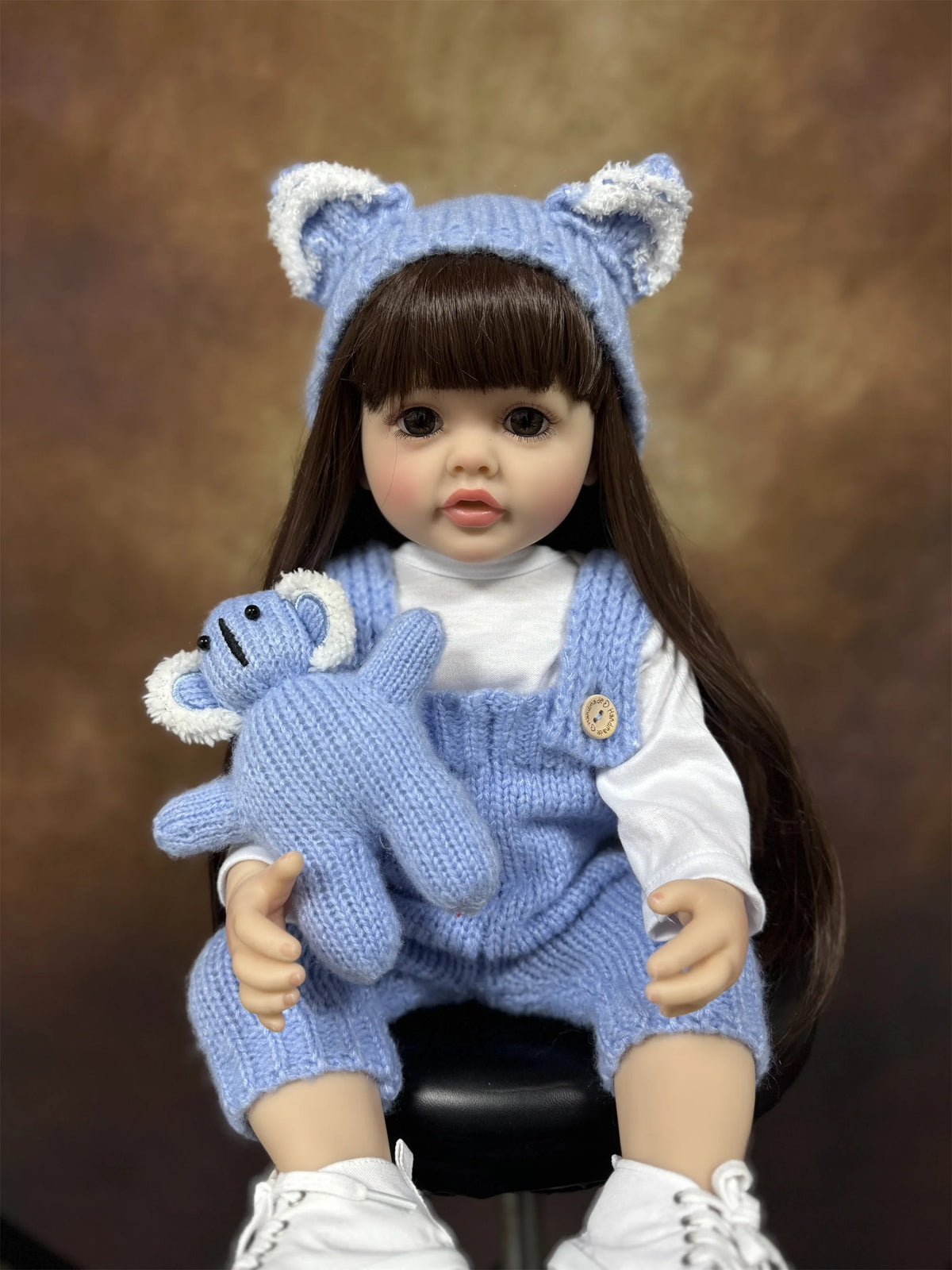 A lifelike silicone baby doll with blue ears and a matching blue knitted outfit.