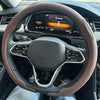 A close-up view of a brown leather steering wheel cover on a car's steering wheel.