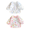A white long-sleeve baby bib featuring a pattern of small yellow and blue animals.