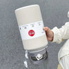 A hand holds a white insulated stainless steel tumbler with a lid and straw, featuring a NEW Sports label.