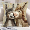 A realistic knitted illustration of two donkeys heads in a close embrace on a beige cushion cover.