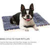A black and white dog is lying on a blue patterned pet mat.