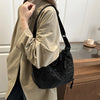 A woman wearing a beige shirt holds a black leopard print crossbody bag.